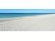 Wide, sandy beach meeting calm ocean waters under a clear blue sky, creating a serene coastal vista at 8779 Midnight Pass Rd # 406H, Sarasota, FL 34242