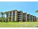 Multi-story condo building with tan and brown exterior and well-manicured lawn at 8779 Midnight Pass Rd # 406H, Sarasota, FL 34242
