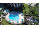 A heart-shaped pool with lounge chairs and umbrellas for shade surrounded by well maintained landscaping at 8779 Midnight Pass Rd # 406H, Sarasota, FL 34242