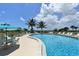A curved pool with lounge chairs and tables offer a space to relax by the beach at 8779 Midnight Pass Rd # 406H, Sarasota, FL 34242