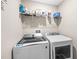 Functional laundry room with modern washer and dryer, plus shelving for storage, making laundry chores a breeze at 9743 Pembrooke Pines Dr, Sun City Center, FL 33573