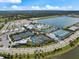 Stunning aerial view showcasing the community clubhouse, pool, tennis courts, and surrounding residences and a lake at 10240 Beach Dune Dr, Englewood, FL 34223
