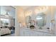 Bright bathroom with dual vanities, gold hardware, stylish mirrors, and view into a bedroom at 10240 Beach Dune Dr, Englewood, FL 34223
