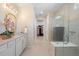 Bright bathroom featuring white vanity with gold hardware, glass shower, and view into the walk-in closet at 10240 Beach Dune Dr, Englewood, FL 34223
