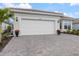 Home with paver driveway and a two-car garage, complemented by decorative landscaping and a tile roof at 10240 Beach Dune Dr, Englewood, FL 34223