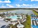 Aerial view of community pool, showcasing ample seating, lush landscaping, and a stunning lake backdrop at 10240 Beach Dune Dr, Englewood, FL 34223