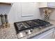 Close-up of the kitchen stovetop with a white tile backsplash and granite countertops at 10240 Beach Dune Dr, Englewood, FL 34223