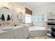 Well-lit bathroom features dual sinks, soaking tub, and decorative fixtures at 12710 Rockrose Gln, Lakewood Ranch, FL 34202