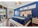 Comfortable bedroom featuring hardwood floors, blue accent wall, and sliding glass doors to lanai at 12710 Rockrose Gln, Lakewood Ranch, FL 34202