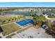 Aerial view of a vibrant blue community basketball court with surrounding green space, palm trees, and lake views at 12726 Rainwashed Loop, Parrish, FL 34219