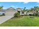 Inviting single-story home with a well-manicured lawn and lush landscaping, including palm trees and flowering plants at 12726 Rainwashed Loop, Parrish, FL 34219