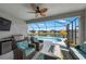 An inviting lanai featuring wicker seating, a ceiling fan, and a summer kitchen overlooking the pool and lake at 12726 Rainwashed Loop, Parrish, FL 34219