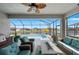 An inviting lanai featuring wicker seating, a ceiling fan, and a summer kitchen overlooking the pool and lake at 12726 Rainwashed Loop, Parrish, FL 34219