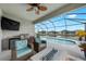 A relaxing lanai featuring wicker seating, a ceiling fan, and a summer kitchen that overlooks the pool and lake at 12726 Rainwashed Loop, Parrish, FL 34219