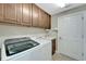 Functional laundry room with washer, dryer, sink, wooden cabinets, and a tiled floor at 130 Bella Vista Ter # 10A, Nokomis, FL 34275