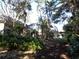 Lush backyard view featuring the home with screened in patio and well maintained landscaping at 1354 Tearose Pl, Sarasota, FL 34239