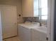 Bright laundry room featuring white front load washer and dryer, window, and sink at 1354 Tearose Pl, Sarasota, FL 34239