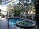 Screened-in pool and hot tub surrounded by lush greenery and serene landscaping at 1354 Tearose Pl, Sarasota, FL 34239