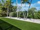 Lush backyard featuring manicured green lawn, palm trees, decorative landscaping, and modern art fixtures at 1909 Field Rd, Sarasota, FL 34231
