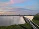 Beautiful waterfront view with dock stretching into tranquil waters under a soft pastel sky at 1930 Bayshore Dr, Englewood, FL 34223