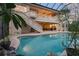 Back of home and outdoor swimming pool enclosed in screened porch with outdoor stairwell to balcony at 1930 Bayshore Dr, Englewood, FL 34223