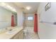 Bathroom with a shower-tub, single sink vanity and red shower curtain at 2402 Scenic Dr, Venice, FL 34293