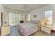 Bedroom featuring a floral bedspread, sliding glass doors, and ample natural light at 2402 Scenic Dr, Venice, FL 34293