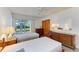 Bedroom with two twin beds, natural light from sliding glass doors, and classic wood furnishings at 2402 Scenic Dr, Venice, FL 34293