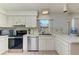 Clean kitchen featuring modern stainless steel appliances, tile flooring, and white cabinets with nice natural lighting at 2402 Scenic Dr, Venice, FL 34293