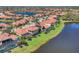 Aerial view of properties showing water view, private pools, manicured lawns, and red tiled roofs at 261 Portofino Dr, North Venice, FL 34275