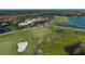 Aerial view of the golf course with lush green fairways, sand traps, and players on the green at 261 Portofino Dr, North Venice, FL 34275