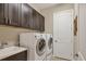 Functional laundry room with modern washer, dryer, sink, and dark cabinets providing ample storage and convenience at 261 Portofino Dr, North Venice, FL 34275