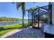 View of the outdoor patio by the water, palm trees, and screened in pool, perfect for relaxation and entertainment at 261 Portofino Dr, North Venice, FL 34275