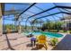Screened-in pool area featuring a hot tub, lush landscaping, and access to the outdoor kitchen at 261 Portofino Dr, North Venice, FL 34275