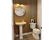 Stylish powder room with wood slat accent wall, round mirror, pedestal sink, and modern toilet at 2904 N Ola Ave, Tampa, FL 33602