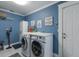 Well-organized laundry room with front-loading machines, countertop, and blue accent walls at 3408 Brookridge Ln, Parrish, FL 34219