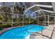 Beautiful pool with a screened-in enclosure, surrounded by lush tropical landscaping at 3408 Brookridge Ln, Parrish, FL 34219