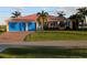 Charming home featuring a well-manicured lawn, a salmon-colored metal roof, and vibrant blue garage doors at 3572 Peace River Dr, Punta Gorda, FL 33983