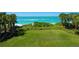 A green grass backyard with tropical trees and beach access at 3909 Casey Key Rd, Nokomis, FL 34275