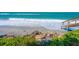 Sandy beach view with blue water, wave action, rocks, and foliage at 3909 Casey Key Rd, Nokomis, FL 34275