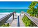 Wooden stairs leading to a sandy beach with clear blue water and lush greenery at 3909 Casey Key Rd, Nokomis, FL 34275
