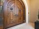 Elegant wood double front doors with bronze accents, framed by a stone archway, offering a grand entrance at 3909 Casey Key Rd, Nokomis, FL 34275