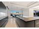 Modern kitchen with sleek black cabinetry, island, stainless steel appliances, and ocean view dining area at 3909 Casey Key Rd, Nokomis, FL 34275