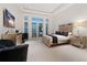 Elegant bedroom with mirrored furniture, upholstered headboard, balcony access, and large windows at 3909 Casey Key Rd, Nokomis, FL 34275