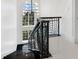 Elegant black staircase with a modern railing design illuminated by a large window and chandelier at 3909 Casey Key Rd, Nokomis, FL 34275