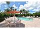 Community pool area featuring lounge chairs, tables, umbrellas, and palm trees at 4141 Entrada Ct, Sarasota, FL 34238