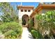 Inviting home entrance with arched doorway, lush greenery, and a well-maintained walkway at 4141 Entrada Ct, Sarasota, FL 34238