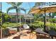 Screened-in patio with table, umbrella, and chairs, surrounded by the lush landscape of the backyard at 4141 Entrada Ct, Sarasota, FL 34238