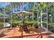 Spacious screened patio with dining table and umbrella, overlooking a lush green landscape at 4141 Entrada Ct, Sarasota, FL 34238