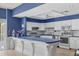 Community kitchen featuring white cabinets, stainless steel appliances, blue countertops, and a breakfast bar at 4753 Independence Dr, Bradenton, FL 34210
